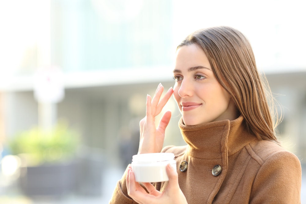 Woman in fall coat applying skincare after a chemical peel in Whittier, CA