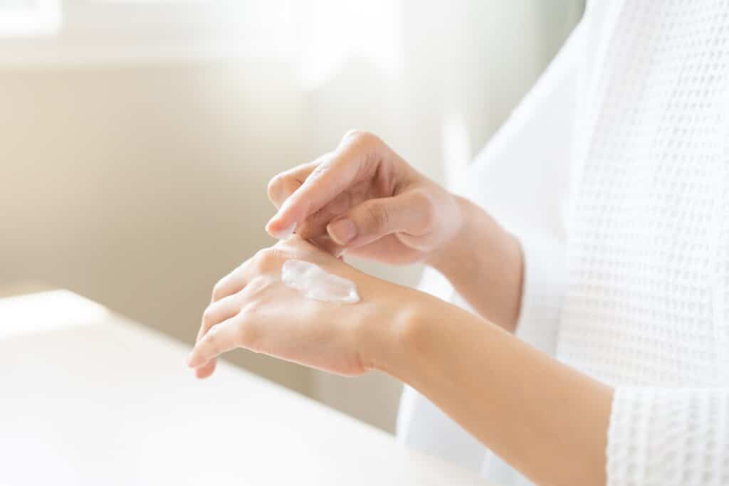 Woman putting moisturizer on her hand after skin lesion removal in Whittier, CA Woman putting moisturizer on her hand after skin lesion removal in Whittier, CA