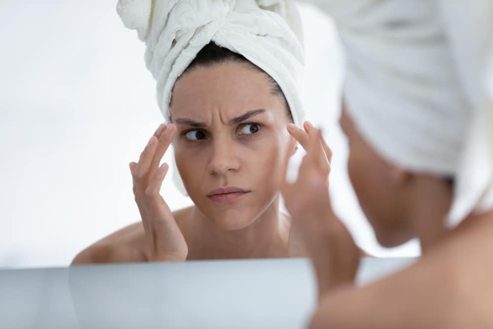 Woman looking in the mirror noticing wrinkles wondering if it's time for Botox