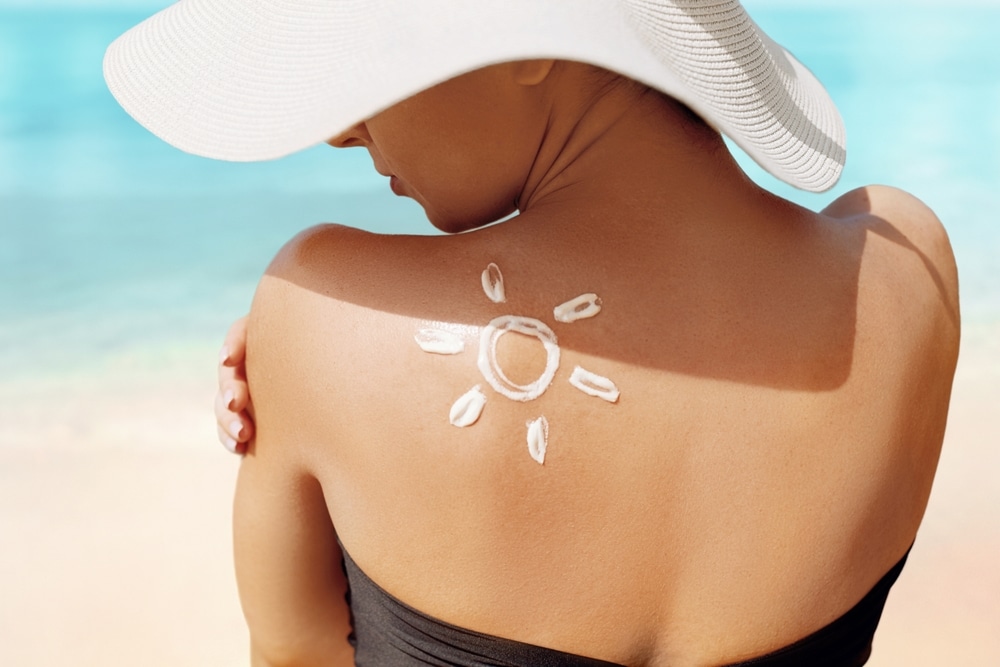 Woman at the beach with sunscreen on her back preventing sun damage